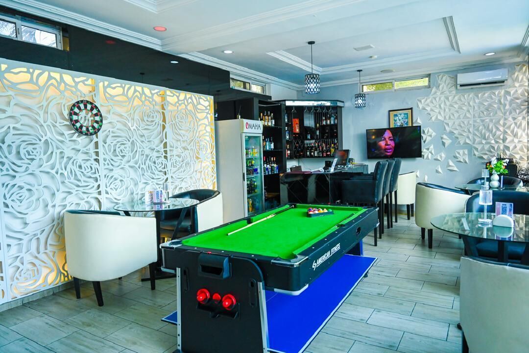 A pool table in a room with a bar area, a television, and a decorative wall.