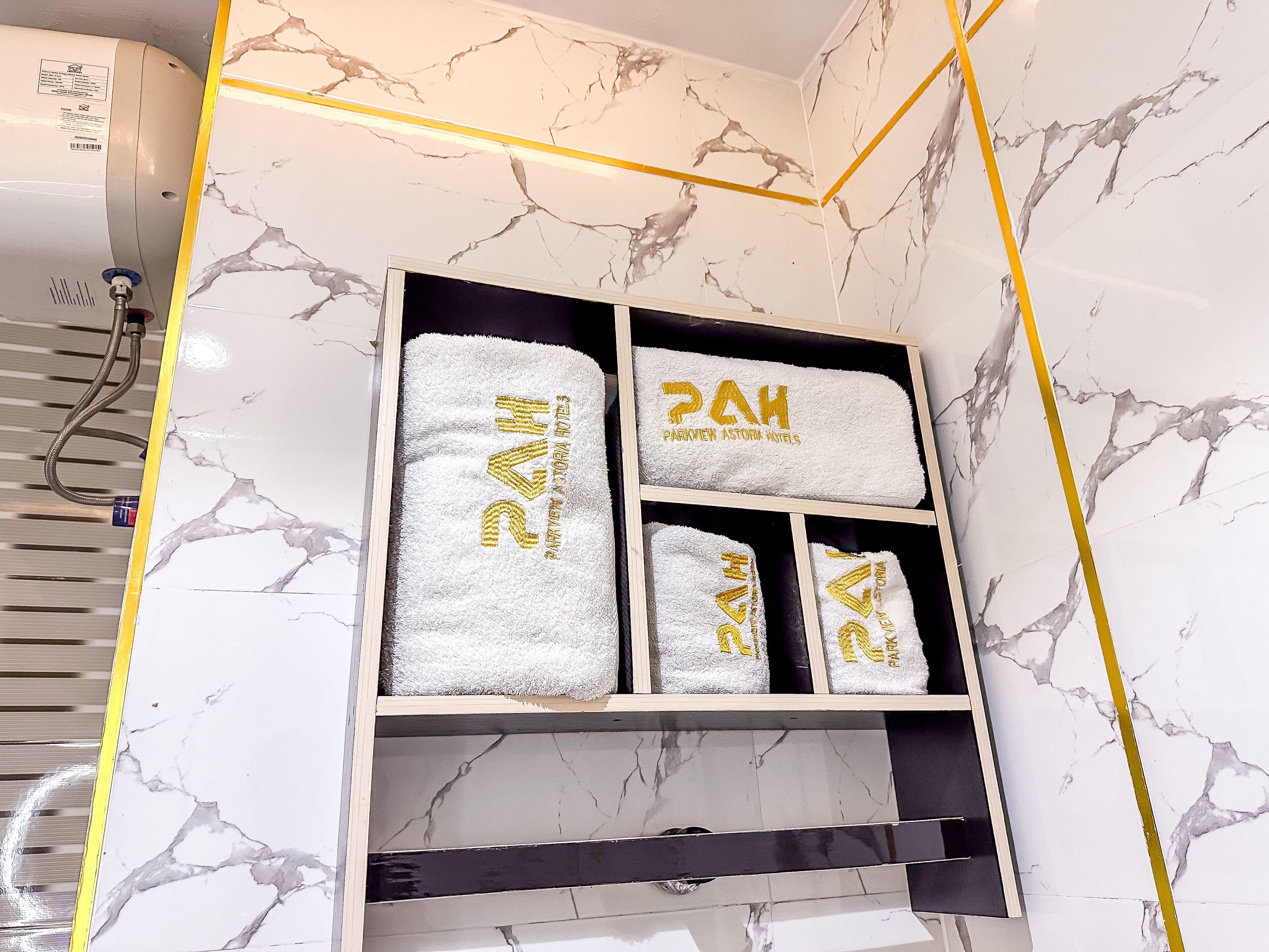 A bathroom with a marble wall, a towel rack with towels, and a shower area.