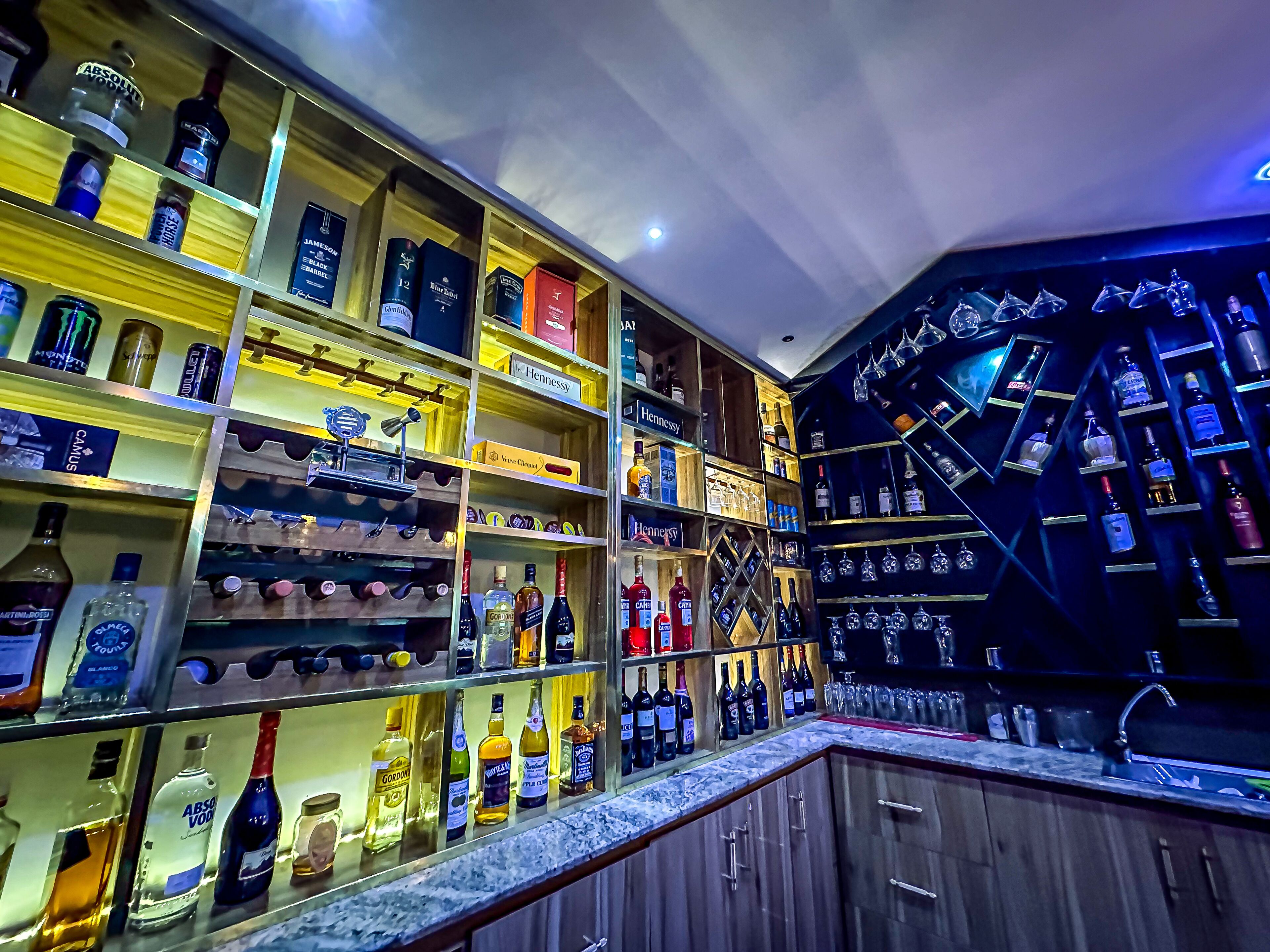 A bar area with shelves of various liquor bottles and glasses.