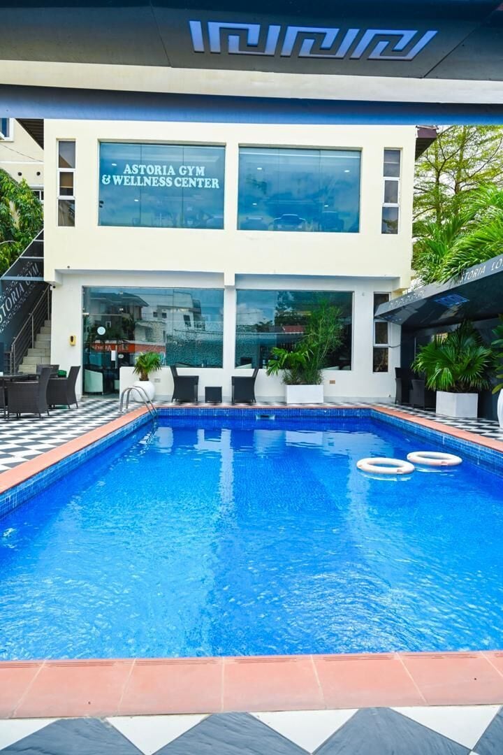 A swimming pool with a checkered border, a wellness center, and a staircase leading to the entrance.