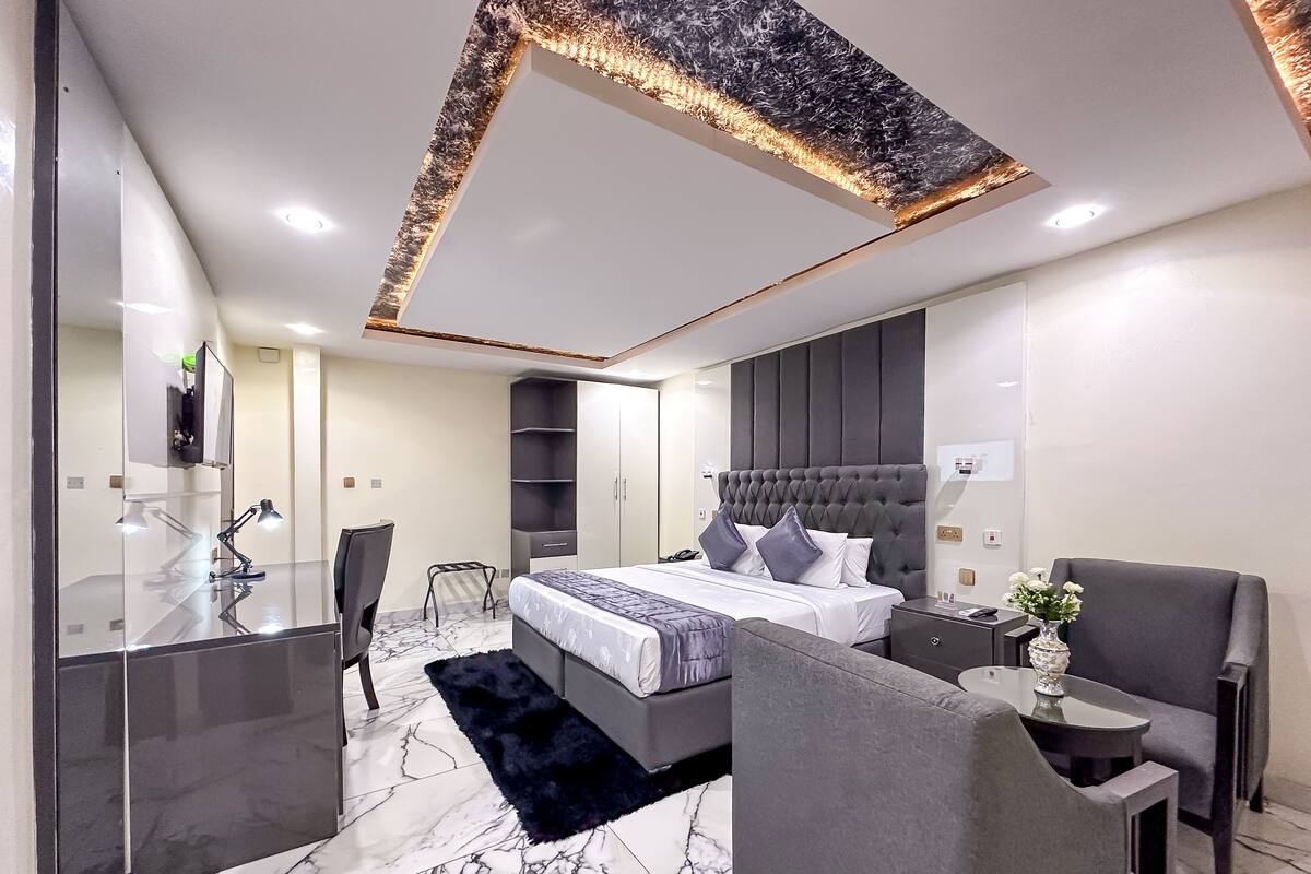 A modern bedroom with a large bed, a desk, and a chair.