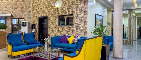 A lobby with blue and yellow seating, a patterned wall, and a staircase.