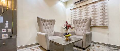 A modern living room with two armchairs, a glass coffee table, and a decorative vase.
