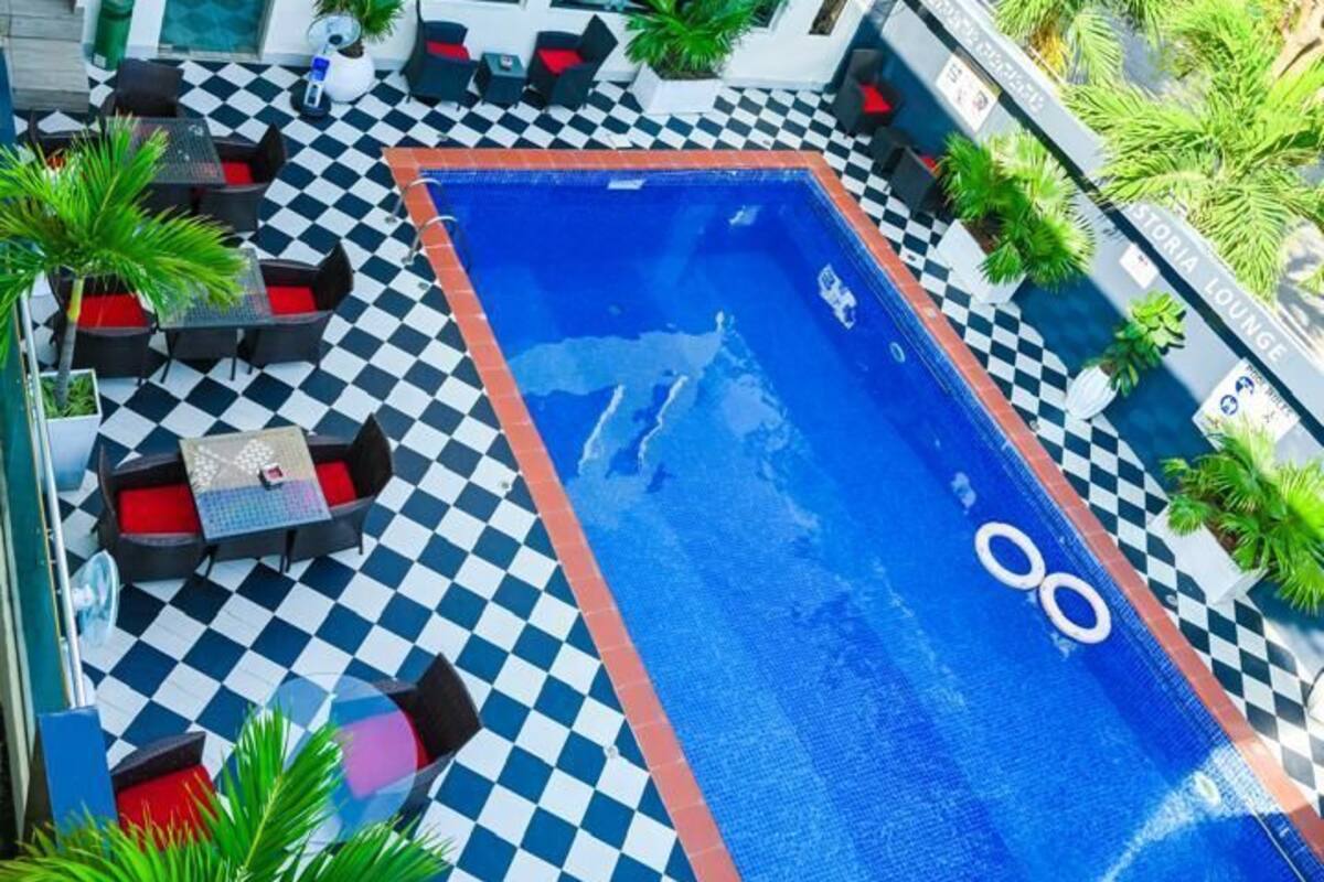 A rooftop pool area with checkered flooring, lounge chairs, and a sign for Astoria Gym & Wellness Center.