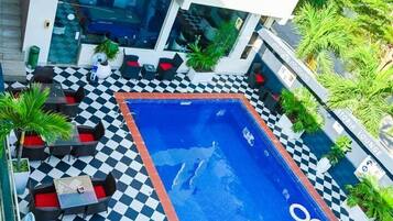 A rooftop pool area with checkered flooring, lounge chairs, and a sign for Astoria Gym & Wellness Center.