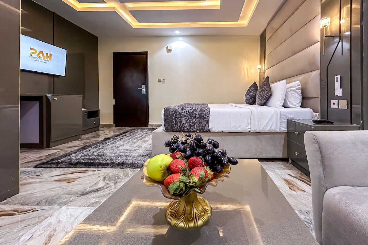A modern hotel room with a bed, bedside table, and a TV on the wall.