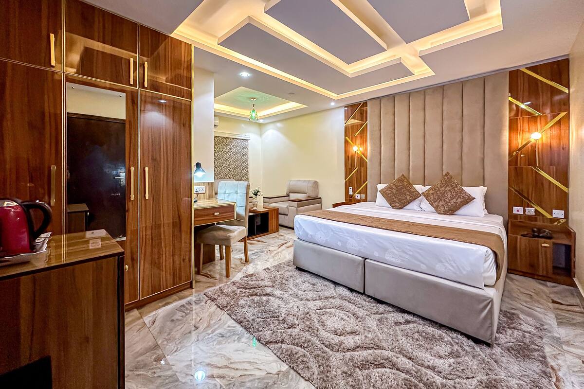 A modern bedroom with a large bed, a desk, and a wardrobe.