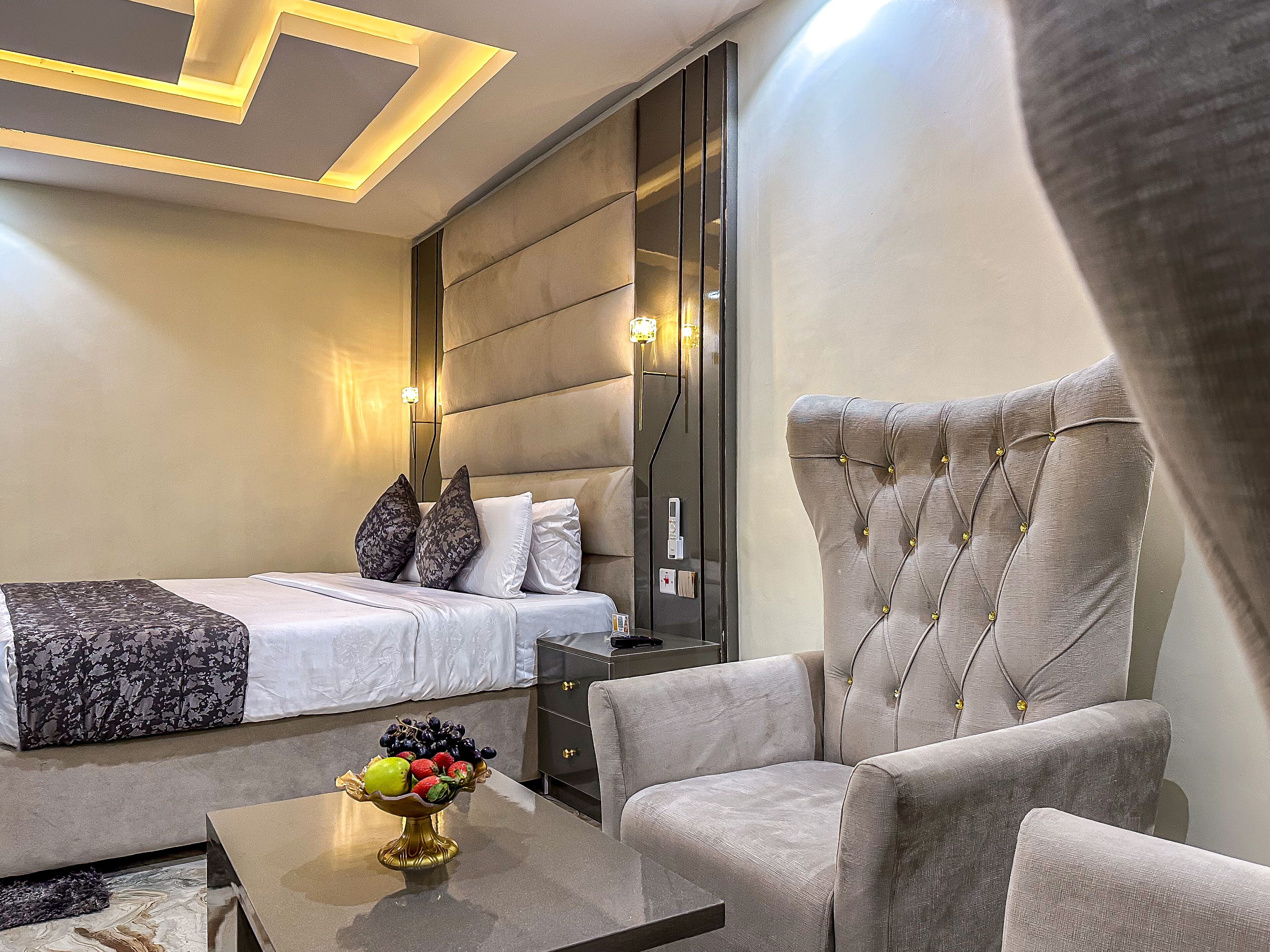 Quarto de hotel com uma cama, área de estar com uma mesa e uma tigela decorativa de frutas.
