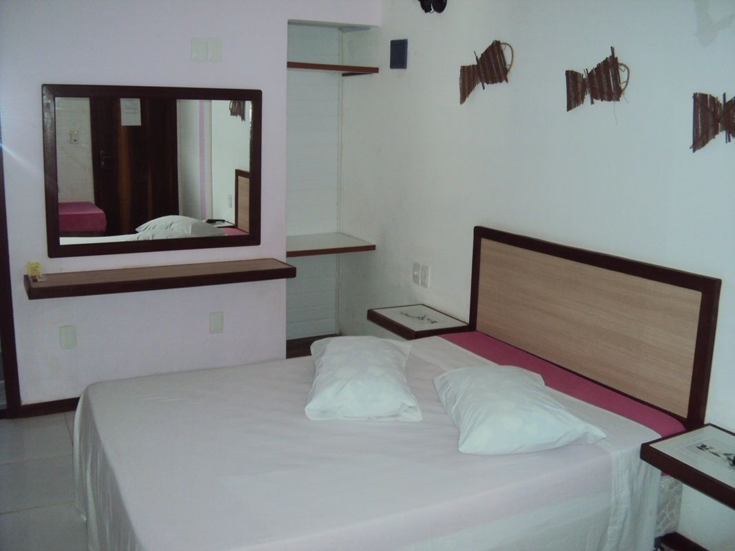 Une chambre à coucher avec un lit, une table de chevet, un miroir et une étagère.