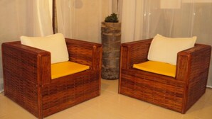 Two wicker chairs with yellow cushions in a room with a stone pillar and sheer curtains. - Pousada Camburi (Morro de Sao Paulo)