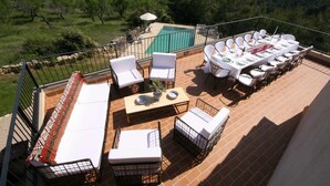 Una terraza con mobiliario exterior, piscina y vistas panorámicas a la montaña.