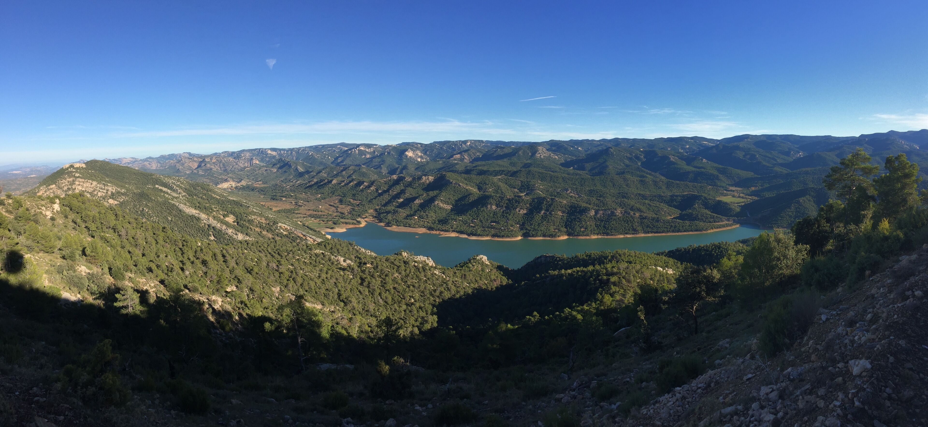 Un paisaje montañoso con un lago rodeado de colinas boscosas.