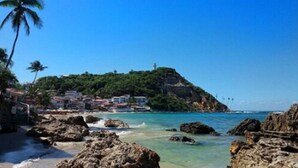 Una zona costera con costas rocosas, aguas azul cristalino y edificios en una ladera.
