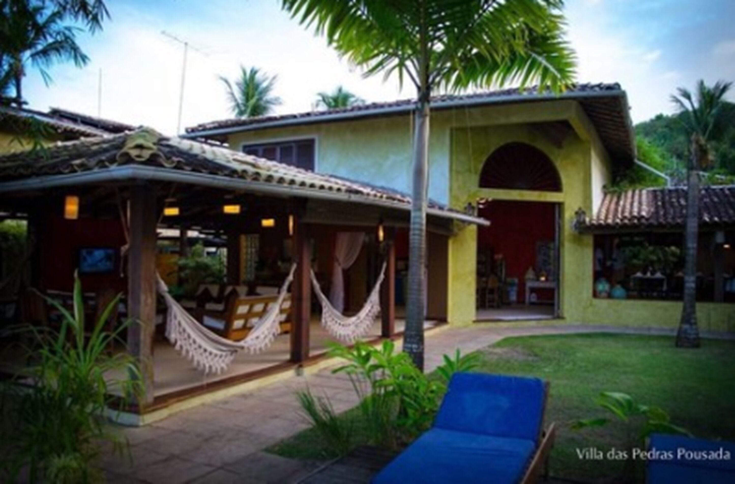 A building with a covered patio area, a hammock, and a blue lounge chair.