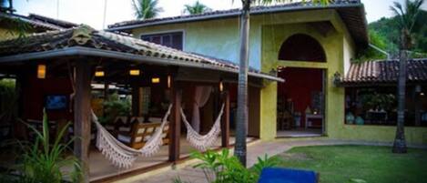 A building with a covered patio area, a hammock, and a blue lounge chair.