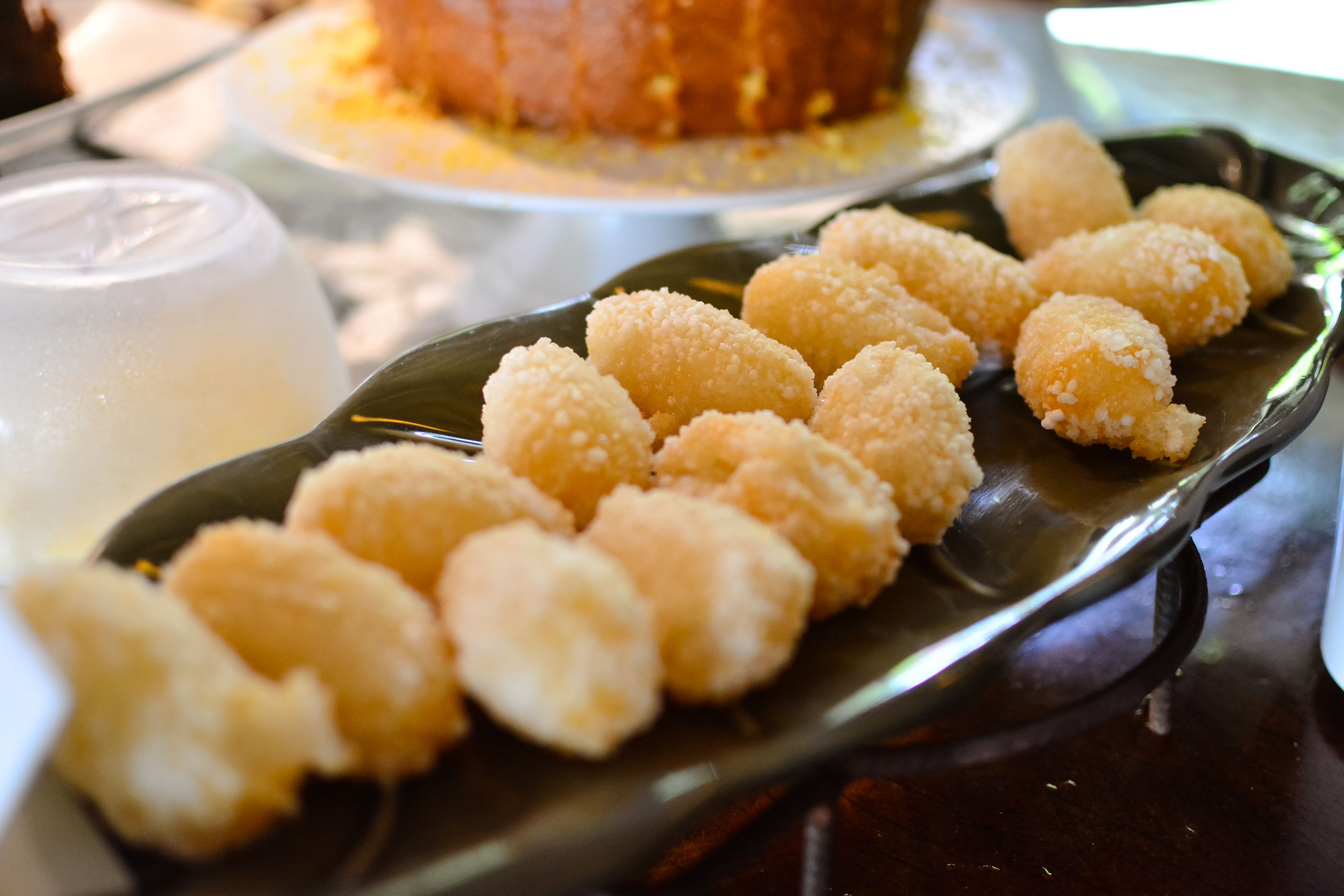 A plate of fried dough balls on a dark plate.