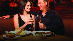 A couple seated at a table with food and wine glasses, in a dimly lit restaurant setting. - Pahrump Nugget Hotel and Casino (Pahrump)