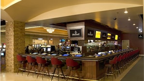 A bar area with multiple gaming machines, a bar counter, and red bar stools. - Pahrump Nugget Hotel and Casino (Pahrump)