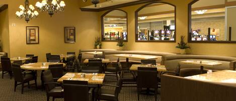 A restaurant with multiple seating areas, including booths and tables, and a bar area visible through the windows.