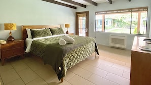 A bedroom with a bed, nightstands, a window, and a view of the outdoors.