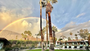 A resort with a pool area, palm trees, and a mountain backdrop.