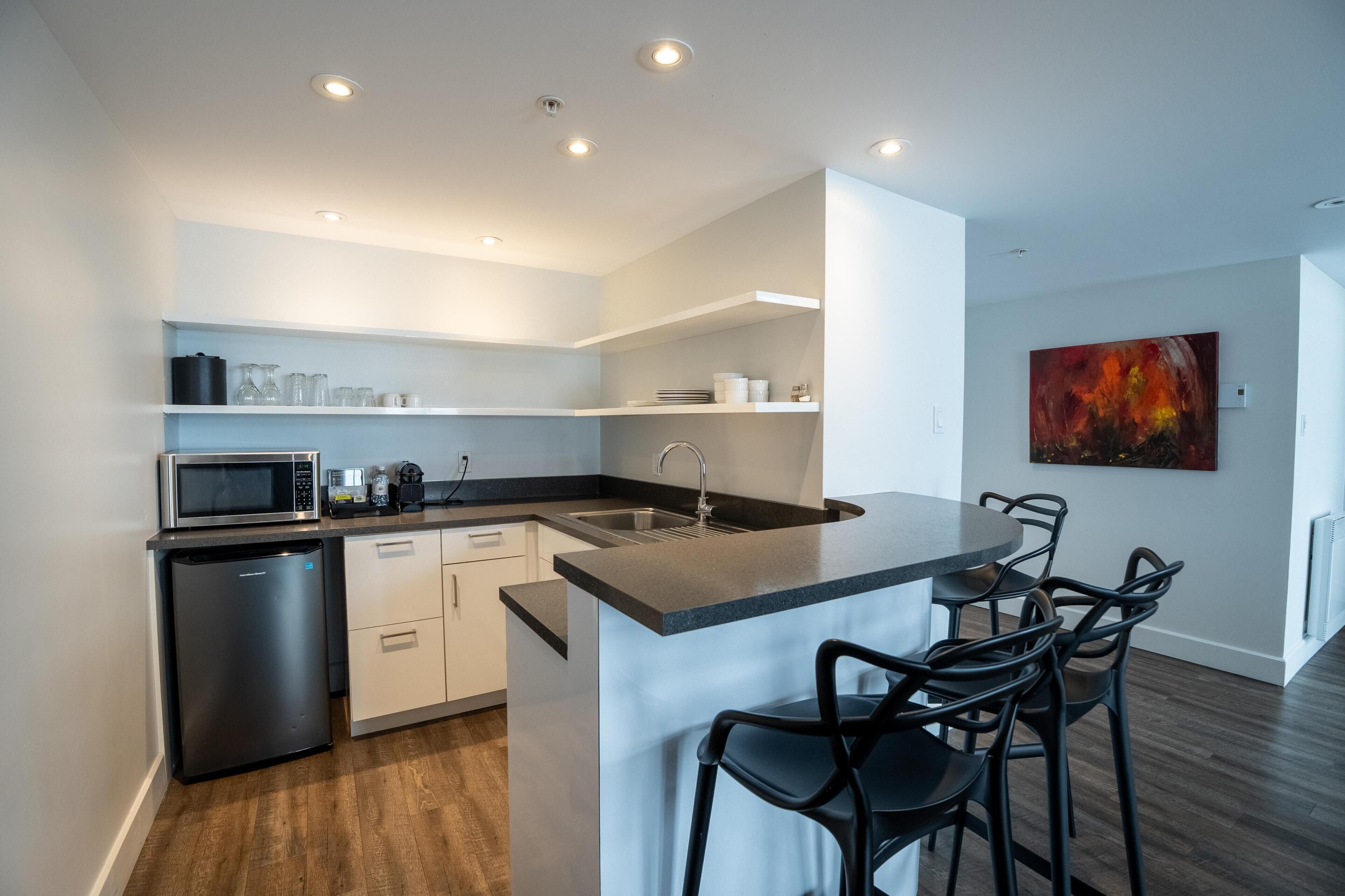 Una cocina moderna con microondas integrado, lavavajillas y una zona de bar con asientos.