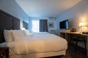 A hotel room with two beds, a desk, a chair, a TV, and a lamp. - Hotel Lac Brome, BW Signature Collection (Lac-Brome)