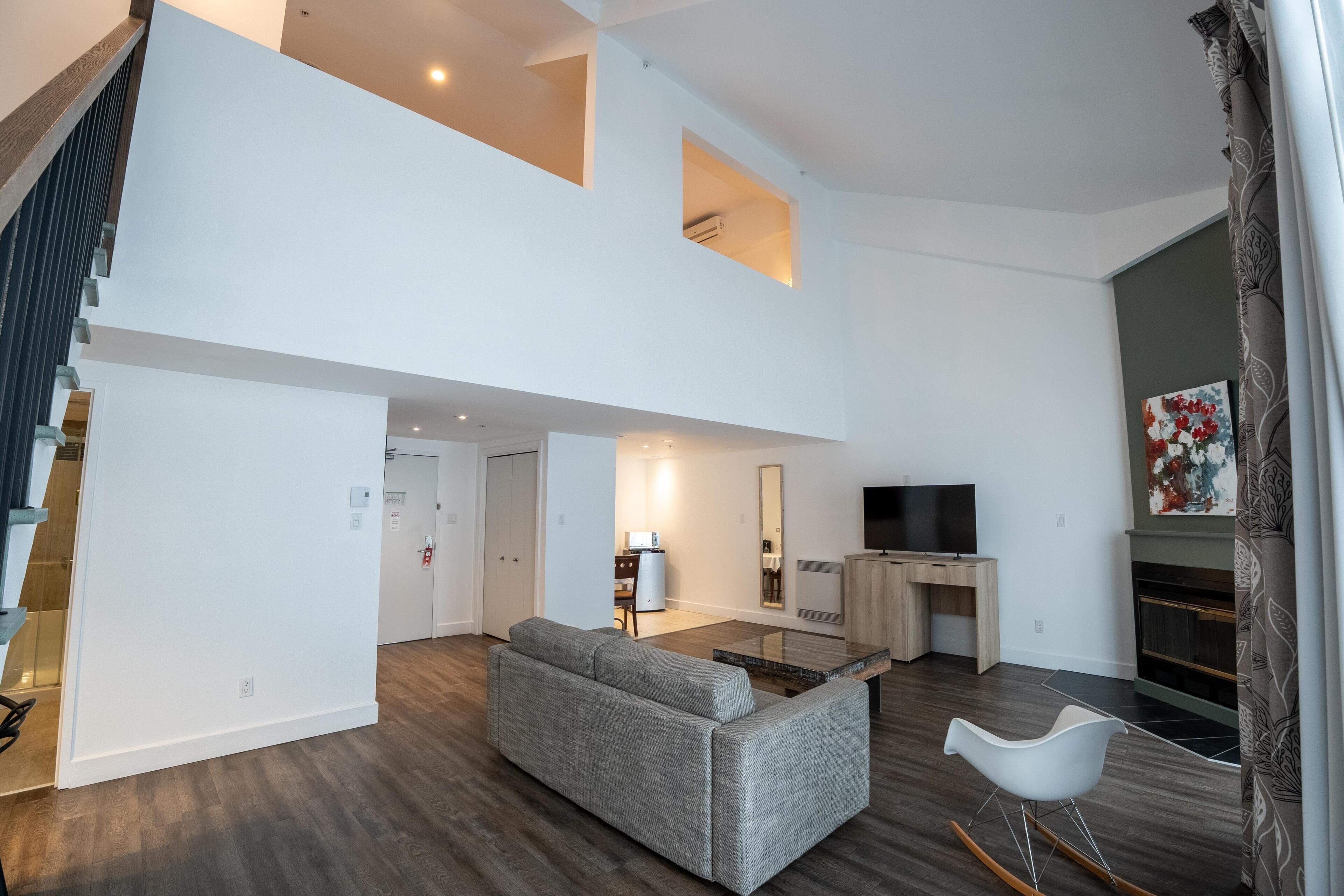 A modern living room with a grey sofa, a TV, and a fireplace.