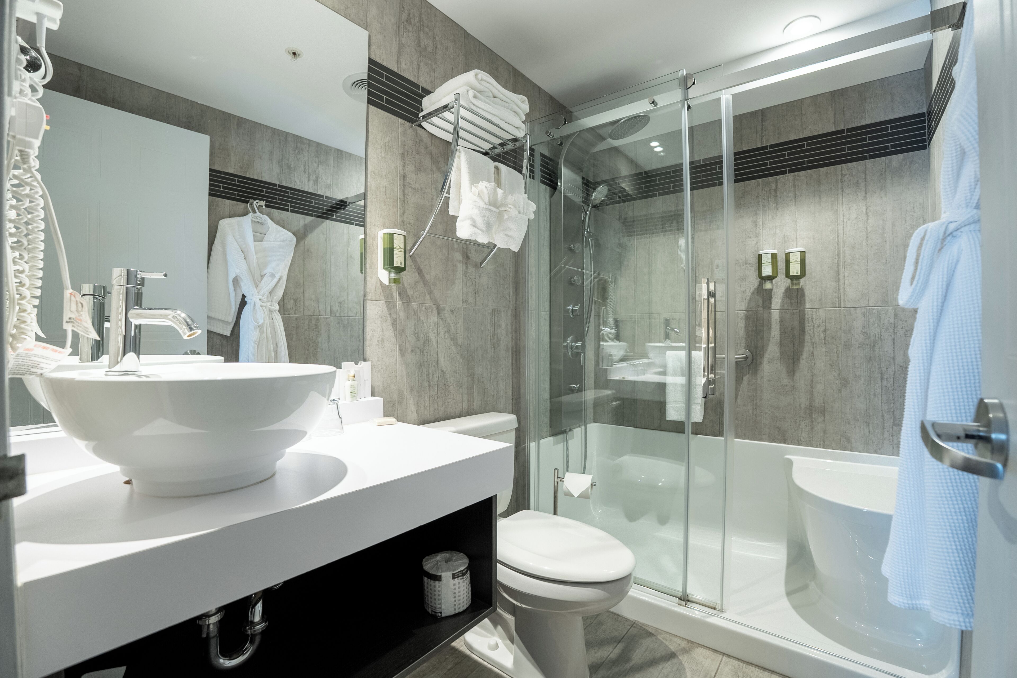 Un baño moderno con un lavamanos grande de color blanco, una ducha con cerramiento de vidrio y un inodoro.