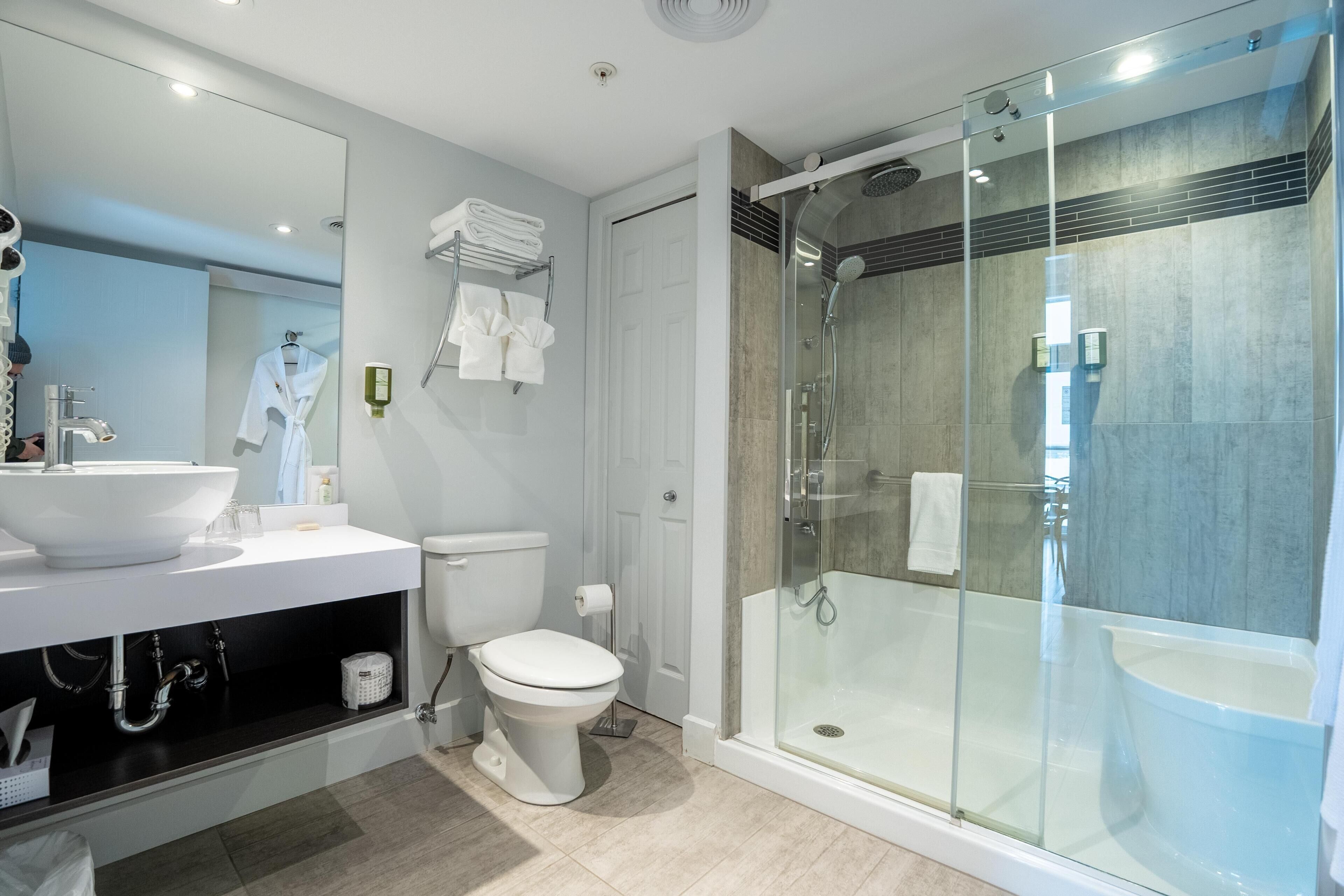 A modern bathroom with a glass-enclosed shower, a white sink, and a toilet.