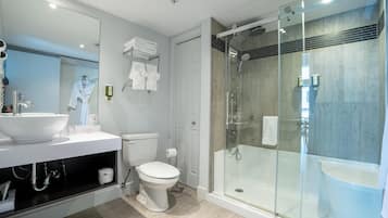 Un baño moderno con ducha de vidrio, lavamanos blanco y un inodoro.