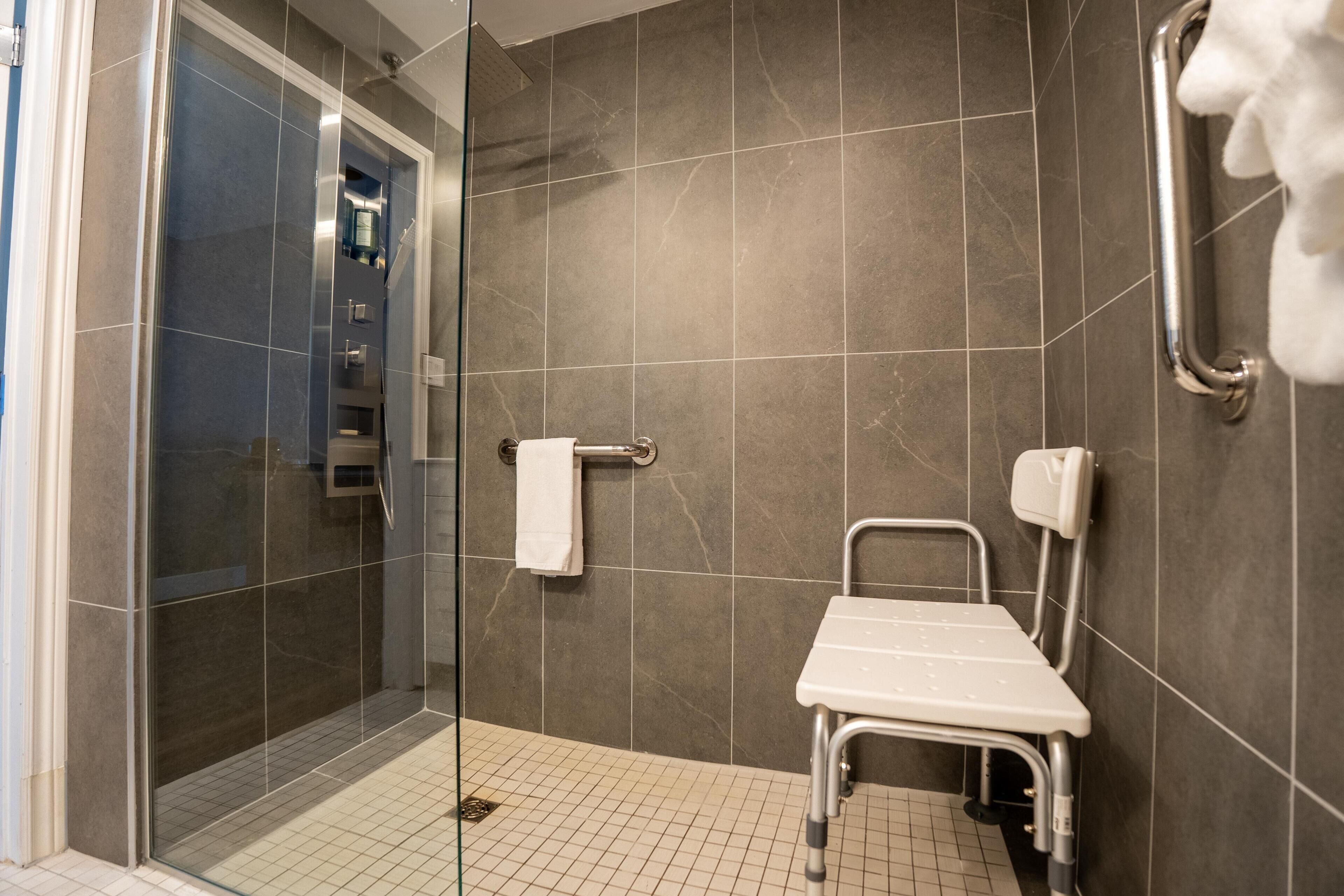 A modern bathroom with a shower, a handrail, and a grab bar.