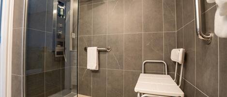 A modern bathroom with a shower, a handrail, and a grab bar.