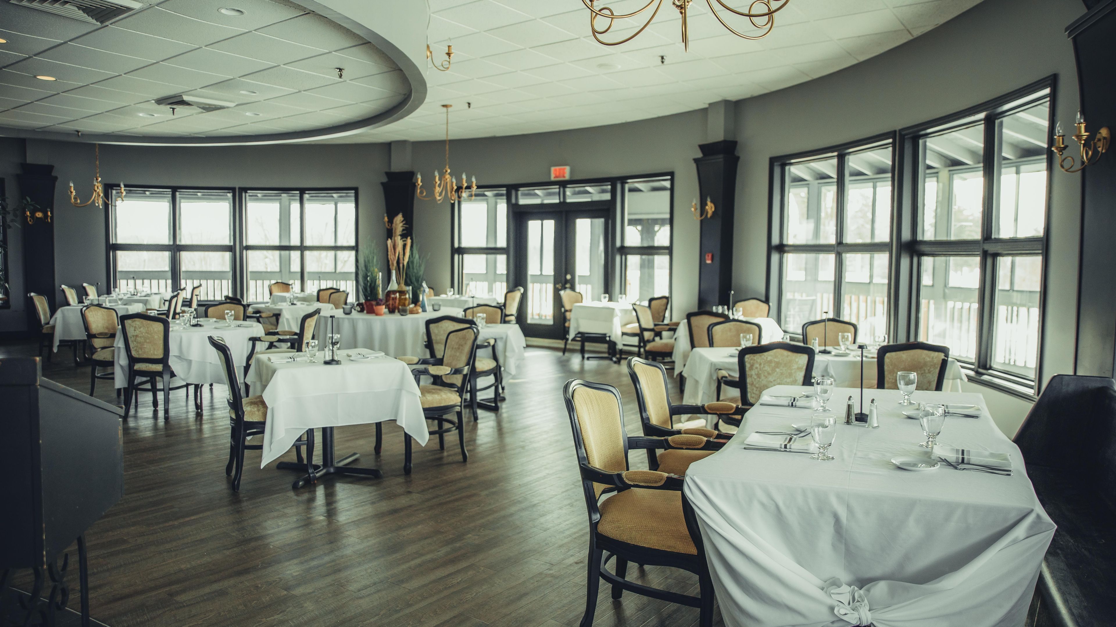 A restaurant with round tables, chairs, and chandeliers.
