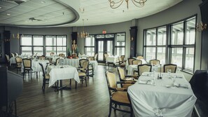 Un restaurante con mesas redondas, sillas y candelabros.