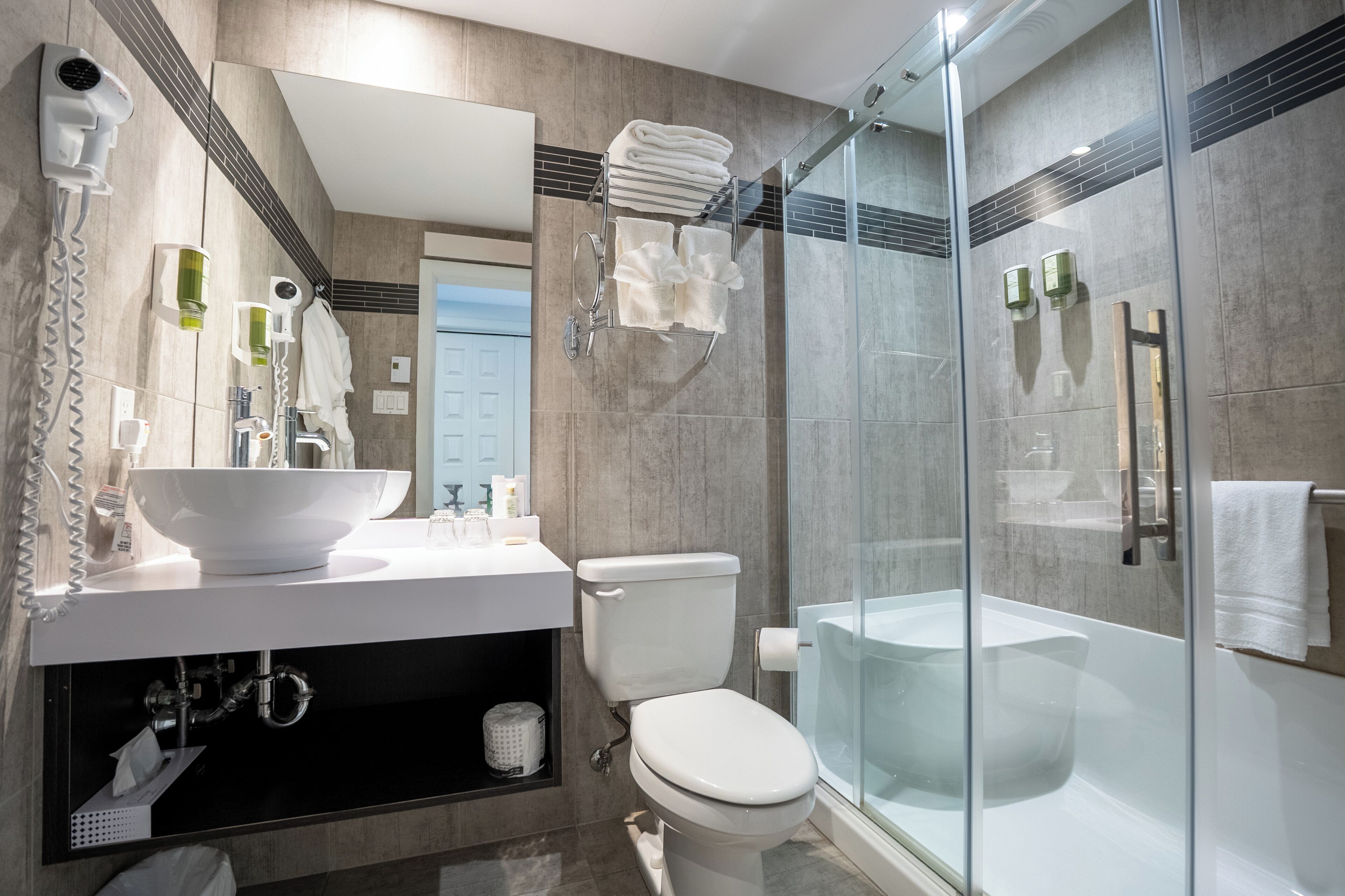 Ein modernes Badezimmer mit einer Duschkabine, einem weißen Waschbecken und einer Toilette.