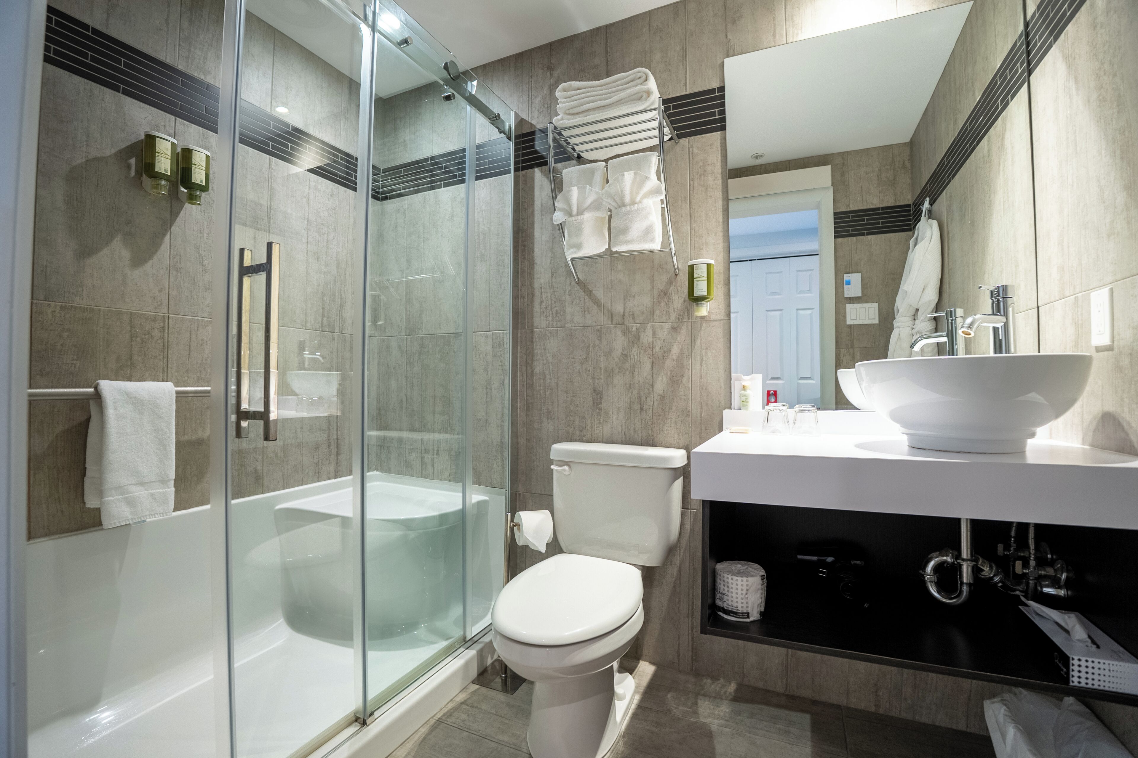 Une salle de bain moderne avec une douche à parois de verre, une baignoire, des toilettes et un lavabo agrémenté d’un grand miroir.