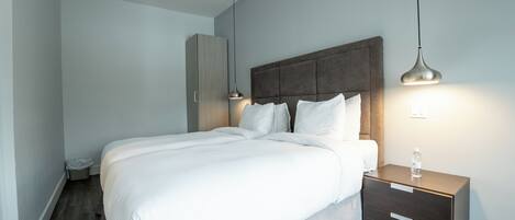 A modern bedroom with a large bed, bedside tables, and a wardrobe.