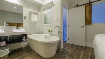 A modern bathroom with a freestanding bathtub, a vanity with a sink, and a large mirror.
