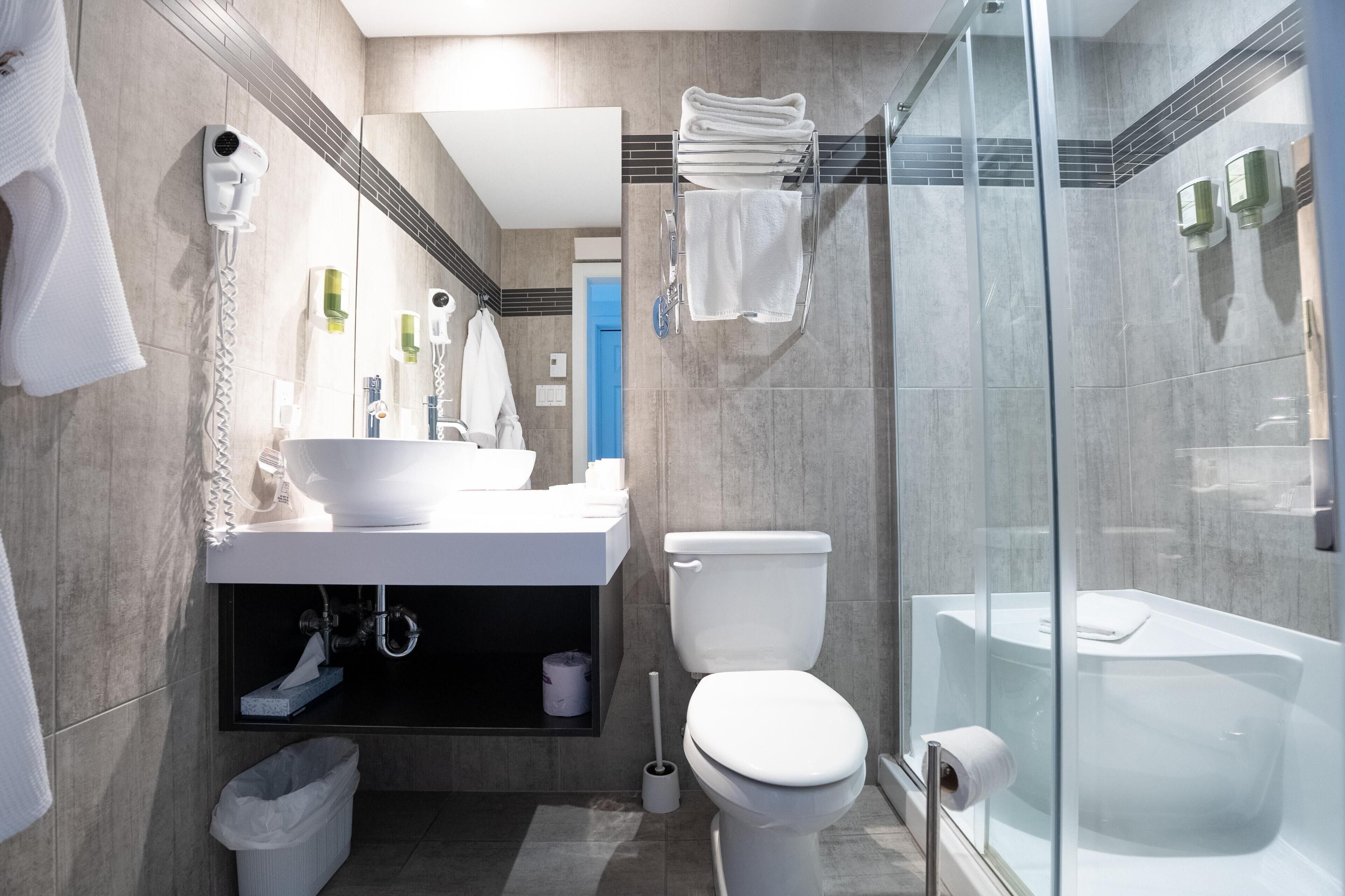 A modern bathroom with a glass-enclosed shower, a white toilet, and a sink area with a towel rack.