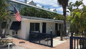 A two-story house with a white exterior, a balcony with a black railing, and an American flag. - Bonita Beach Inn and Suites (Bonita Springs)