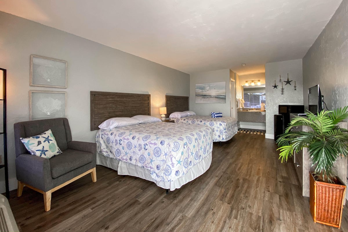 Ein Hotelzimmer mit zwei Betten, einer Couch, einem Fernseher und einem Kamin.