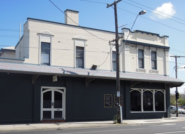 A two-story building with a flat roof and a dark facade. - Plough Hotel (Footscray)