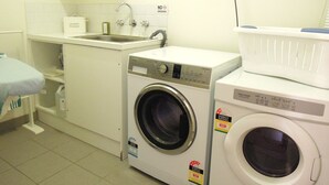 Ein Waschraum mit zwei Waschmaschinen mit Frontlader, einem Waschbecken und einem Waschmittelspender.