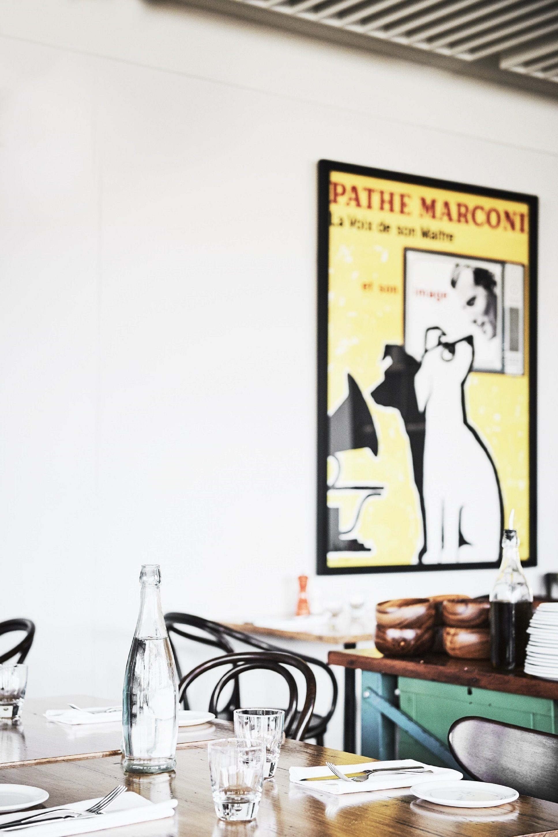 A dining table with a poster, a bottle, and glasses.