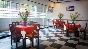 A restaurant with checkered flooring, wooden chairs, and tables with red tablecloths. - Hotel Max (Mexico City)