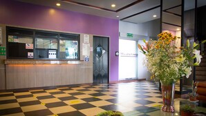 A checkered floor, a reception desk, a large vase with flowers, and a staircase in the background. - Hotel Max (Mexico City)