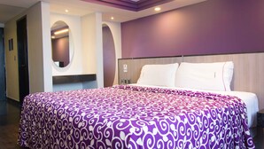 A hotel room with a large bed, a mirror, and a wooden headboard. - Hotel Max (Mexico City)