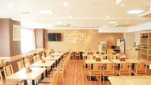 A spacious restaurant with wooden tables and chairs, a large wall mural, and a television screen. - Central Hotel Imari (Imari)