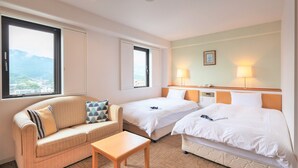 A hotel room with two beds, a sofa, a small table, and a view of the city. - Central Hotel Imari (Imari)